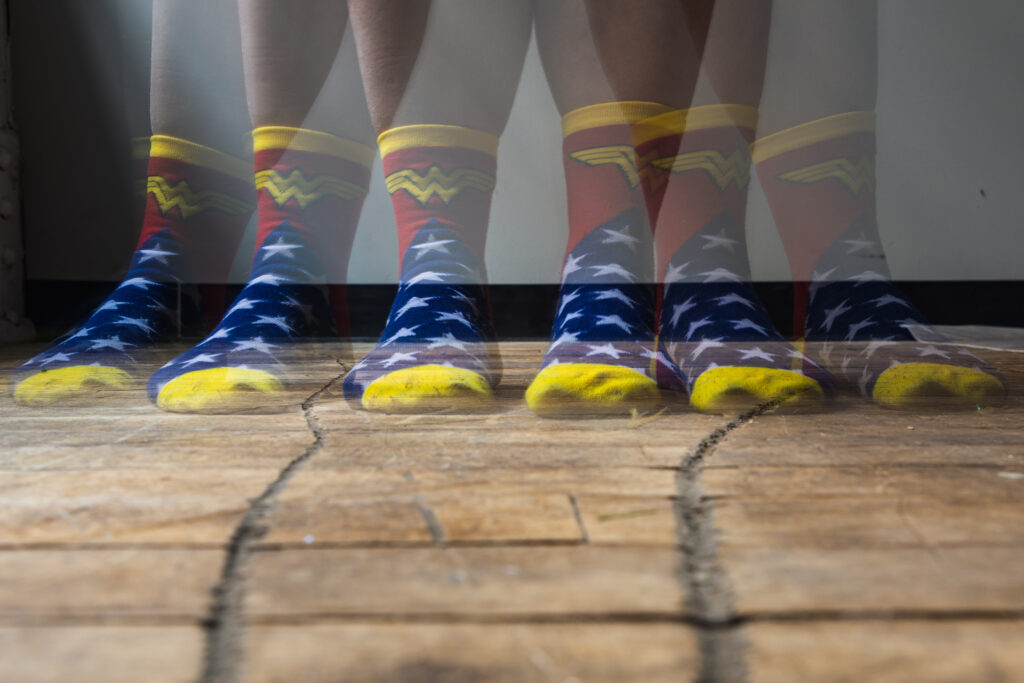 Blur the Action: An image of six slightly transparent feet covered in Wonder Woman socks.