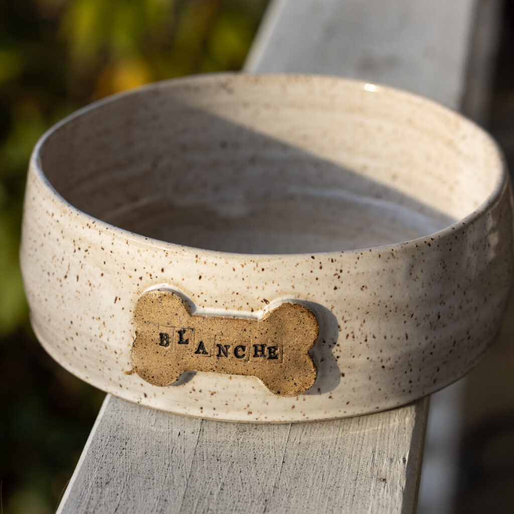Ceramic dog bowl from Gina Desantis Ceramics, located in the Cleveland Ohio area. The name "Blanche" is in typeface on a dog bone shape on the front of the bowl.